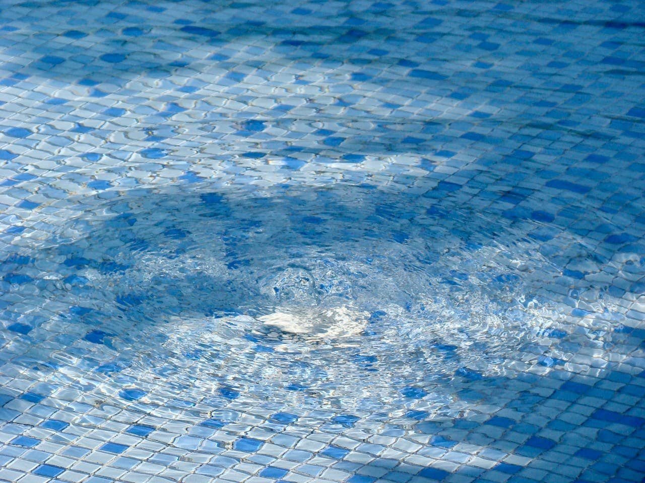 Protective concrete pool surface with slip-resistant blue tile design for safety and durability in swimming pools.