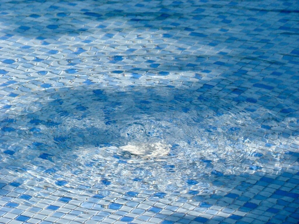 Blue tiled swimming pool with a whirlpool feature.